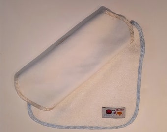 Puede incluir: Un babero de tela blanco para bebé con ribete azul y un pequeño logotipo que dice "SENSOO" con un círculo rojo y una corona amarilla.