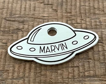 May include: Silver metal UFO dog tag with the name MARVIN engraved on it.