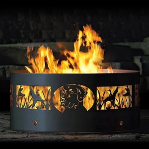 May include: A black metal fire pit with cutouts of a dog and birds. The fire pit is round and has a rustic design. The fire pit is lit and the flames are visible.