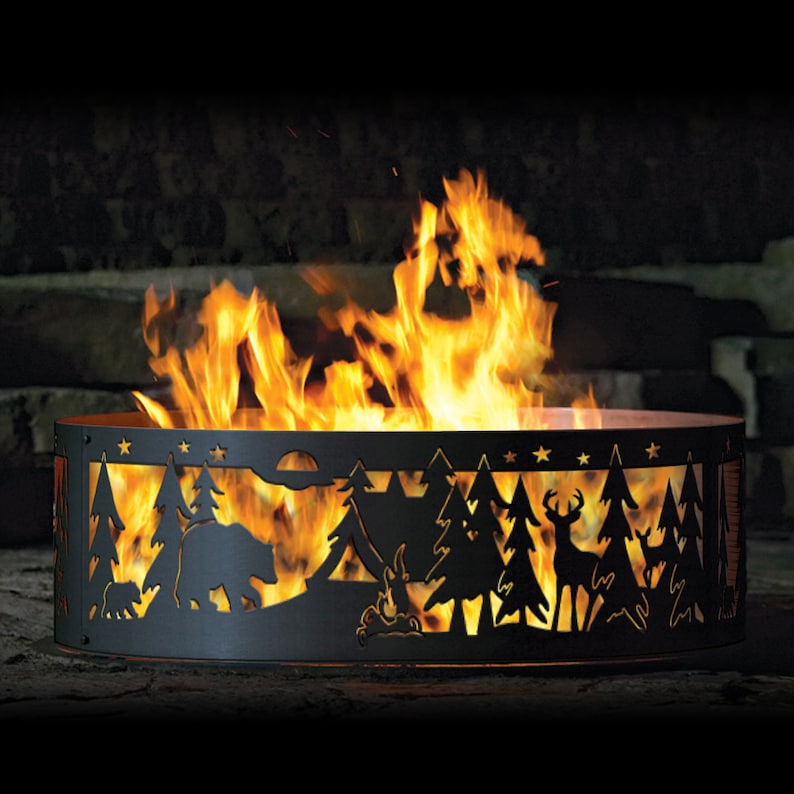 Puede incluir: Un pozo de fuego de metal negro con un dise&ntilde;o recortado de una escena de bosque, que incluye &aacute;rboles, un oso, un ciervo y estrellas. El pozo de fuego est&aacute; lleno de llamas.
