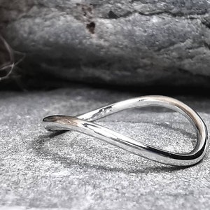 May include: A polished silver ring with a continuous, flowing design. The ring's shape is a smooth, unbroken loop, reflecting light and creating a minimalist aesthetic. The ring is likely made of sterling silver, and is suitable for everyday wear.