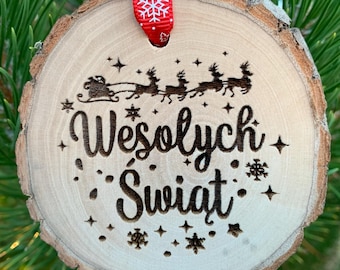 Könnte beinhalten: Runder Weihnachtsbaumschmuck aus Holz mit natürlichem Rindenrand. Das Ornament zeigt ein Rentierschlitten-Design und den Schriftzug "Wesołych Świąt". Ein rotes Band mit Schneeflockenmuster zum Aufhängen.