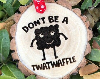 May include: A wooden Christmas ornament with the text "Don't be a twatwaffle" and a cartoon character with a smiling face.