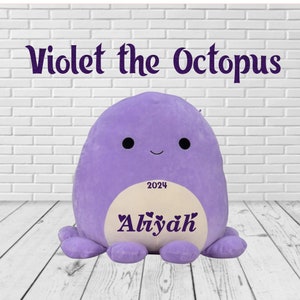 May include: A plush, lavender octopus toy with the text "Violet the Octopus" above it. The octopus has a cream-colored belly with the name "Aliyah" and the year "2024" printed on it. The toy has a smiling face and eight tentacles.