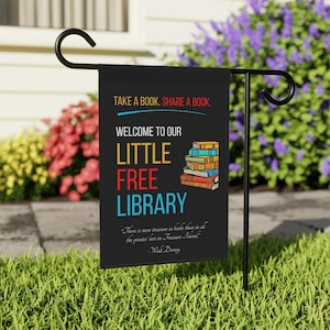 May include: Black garden flag with the text "TAKE A BOOK. SHARE A BOOK." and "WELCOME TO OUR LITTLE FREE LIBRARY." A stack of books is illustrated on the right. A quote by Walt Disney is at the bottom.