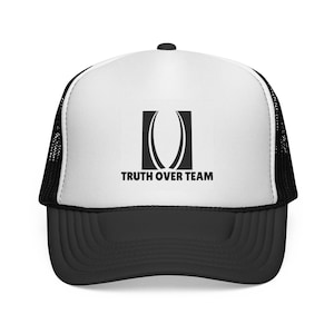 May include: A black and white trucker hat with a curved brim. The hat features a white front panel with a black logo and the text "TRUTH OVER TEAM". The sides and back are black mesh.