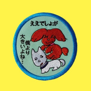 Pode incluir: Patch bordado redondo com um desenho de cão de desenho animado. O patch apresenta um cão vermelho em cima de um cão branco, sobre um fundo azul claro com texto japonês e uma borda azul. O fundo é amarelo.