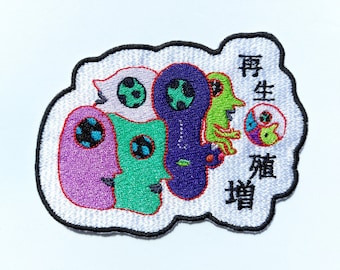 May include: Embroidered patch with a white background and a colorful design of four cartoon characters. The characters are green, purple, pink, and white. The text "再生 煩悩" is embroidered in black on the white background.