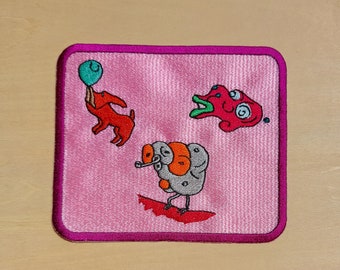 May include: Pink embroidered patch with a red dog holding a blue balloon, a gray creature with orange spots, and a red monster with a green mouth and one eye.