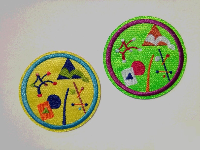 K&ouml;nnte beinhalten: Zwei gestickte Aufn&auml;her mit abstrakten geometrischen Mustern. Der erste Aufn&auml;her ist gelb mit einem blauen, gr&uuml;nen und roten Muster. Der zweite Aufn&auml;her ist gr&uuml;n mit einem roten, orangen und wei&szlig;en Muster.