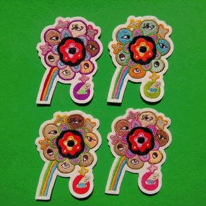 May include: Four colorful embroidered iron-on patches featuring a flower with a large eye in the center surrounded by smaller eyes. Each patch has a rainbow-colored stem and a small white figure at the bottom.