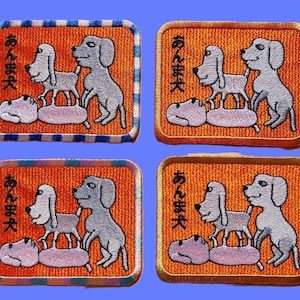 Puede incluir: Cuatro parches bordados con un borde blanco y un fondo naranja. Cada parche presenta una frase japonesa "あんま好き" y una imagen de dibujos animados de tres perros apilados uno encima del otro.