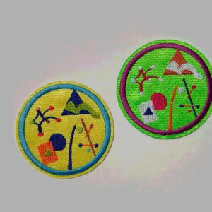 K&ouml;nnte beinhalten: Zwei runde gestickte Aufn&auml;her mit gr&uuml;nem und gelbem Hintergrund. Die Aufn&auml;her zeigen abstrakte Designs mit geometrischen Formen und Linien in verschiedenen Farben, darunter Rot, Blau und Wei&szlig;.