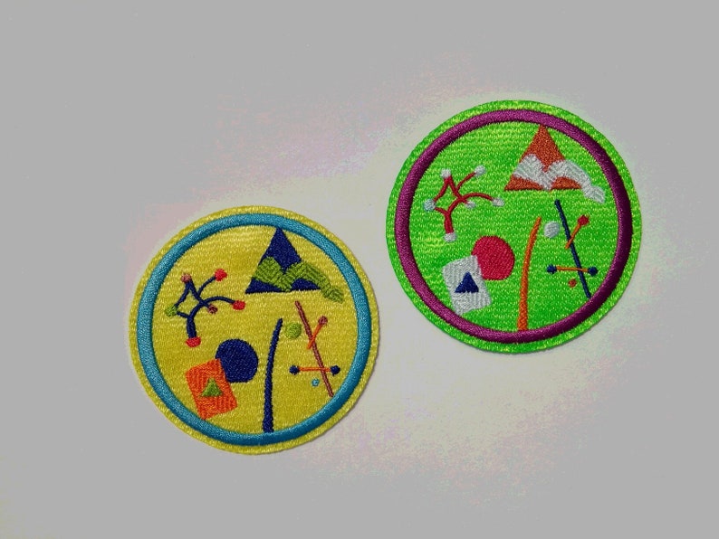 K&ouml;nnte beinhalten: Zwei runde gestickte Aufn&auml;her mit gr&uuml;nem und gelbem Hintergrund. Die Aufn&auml;her zeigen abstrakte Designs mit geometrischen Formen und Linien in verschiedenen Farben, darunter Rot, Blau und Wei&szlig;.