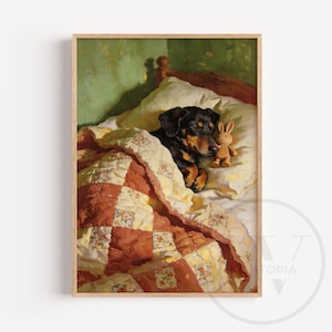 May include: A framed print of a dog sleeping in a bed, covered by a quilt. The dog is black and brown, and a small stuffed bunny rests beside it. The quilt is a patchwork design with red and cream squares.