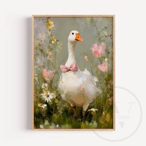 May include: A framed art print of a white goose wearing a pink bow tie, standing in a field of flowers. The artwork has a soft, painterly style with a muted color palette of greens, pinks, and yellows. The goose has an orange beak.