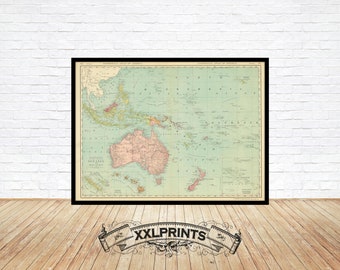 May include: A vintage map of Oceania and Malaysia, printed on a light blue background with brown and red accents. The map shows the islands of Indonesia, Australia, New Zealand, and surrounding islands. The map is framed in a black frame.