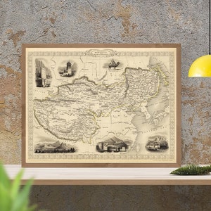 Peut inclure: Une carte vintage de l'Asie centrale, imprimée en noir et blanc, avec une bordure décorative et des images insérées de divers monuments. La carte est encadrée dans un cadre en bois brun et exposée sur une étagère.