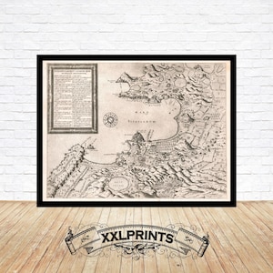 May include: Framed vintage map print with intricate details. The sepia-toned map features a coastal landscape, text, and a compass rose. The print is in a black frame, displayed against a white brick wall and wooden floor. The banner at the bottom reads "XXLPRINTS".