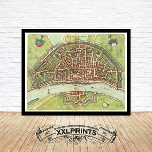 May include: A framed vintage map of a city, featuring a detailed layout of streets, buildings, and fortifications. The map is in shades of green, brown, and beige, with text in Latin. The frame is black, and the print is displayed against a white brick wall.