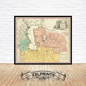 Op de afbeelding: Ingelijste vintage kaartprint met een zwarte rand. De kaart toont een gedetailleerde, kleurrijke weergave van een historische regio, met verschillende kleuren die verschillende gebieden markeren. De print wordt weergegeven op een houten vloer tegen een witte bakstenen muur.
