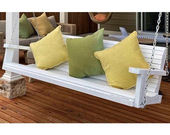 May include: White wooden porch swing with a white cushion and three yellow and green throw pillows. The swing is hanging from chains and is on a wooden deck.