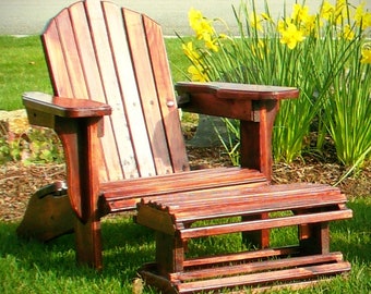 May include: A wooden adirondack chair with a matching footrest. The chair and footrest are both stained a dark brown color. The chair is sitting on a grassy lawn with yellow flowers in the background.