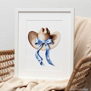 Puede incluir: Una pintura de acuarela de un sombrero de vaquero marr&oacute;n con una cinta de patr&oacute;n azul y blanco atada alrededor de la corona.