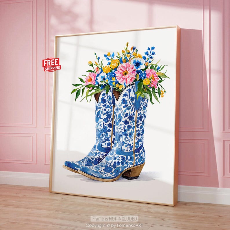 May include: A framed art print featuring a pair of blue and white cowboy boots filled with colorful flowers. The boots have a floral pattern. The flowers are pink, yellow, and blue. The artwork is displayed against a white background.