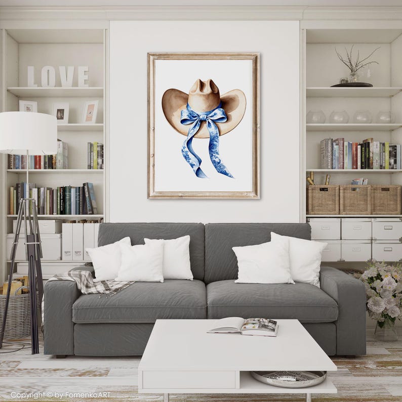 Puede incluir: Una pintura de acuarela de un sombrero de vaquero marr&oacute;n con una cinta azul atada en un lazo. El sombrero est&aacute; sobre un fondo blanco.