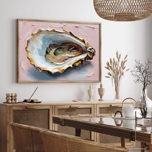 May include: An oyster shell painting in a wooden frame. The artwork features a detailed depiction of an oyster shell with a textured, impasto style. The background is a soft pink, and the shell has gold, white, and blue tones.