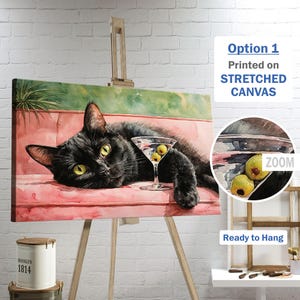May include: A canvas print depicting a black cat relaxing on a pink sofa, with a martini glass containing olives. The artwork is displayed on an easel. Text on the print reads "Option 1 Printed on STRETCHED CANVAS" and "Ready to Hang".