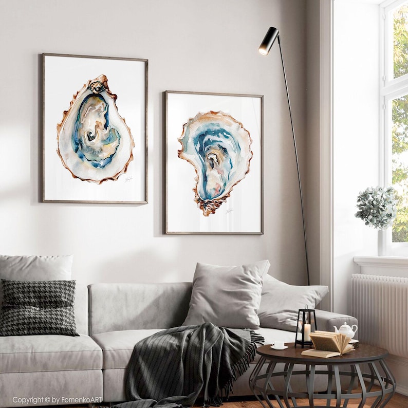 Puede incluir: Dos impresiones enmarcadas de acuarela de conchas de ostra. La obra de arte presenta tonos de azul, marr&oacute;n y blanco, con detalles intrincados. Los marcos son de color marr&oacute;n neutro y las impresiones se exhiben en una pared blanca.