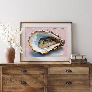 May include: A framed painting of an oyster shell. The artwork features a textured, close-up view of the shell with shades of blue, gold, and brown against a pink background. The painting is displayed on a wooden dresser.