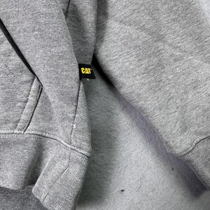 May include: A set of three ceramic mugs with a speckled, matte finish. The mugs are in shades of cream, light gray, and dark gray. Each mug has a simple, minimalist design and a rounded handle. The mugs are stacked on top of each other.