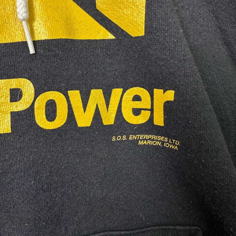 May include: Black hooded sweatshirt with the word "Power" in large yellow letters. The sweatshirt also features the text "S.O.S. Enterprises Ltd. Marion, Iowa" in smaller yellow letters.