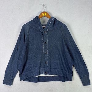 Könnte beinhalten: Ein marineblauer Kapuzenpullover mit Knopfleiste vorne. Der Pullover hat lange Ärmel und eine lockere Passform. Er hängt an einem Holzbügel vor einem hellgrauen Hintergrund.