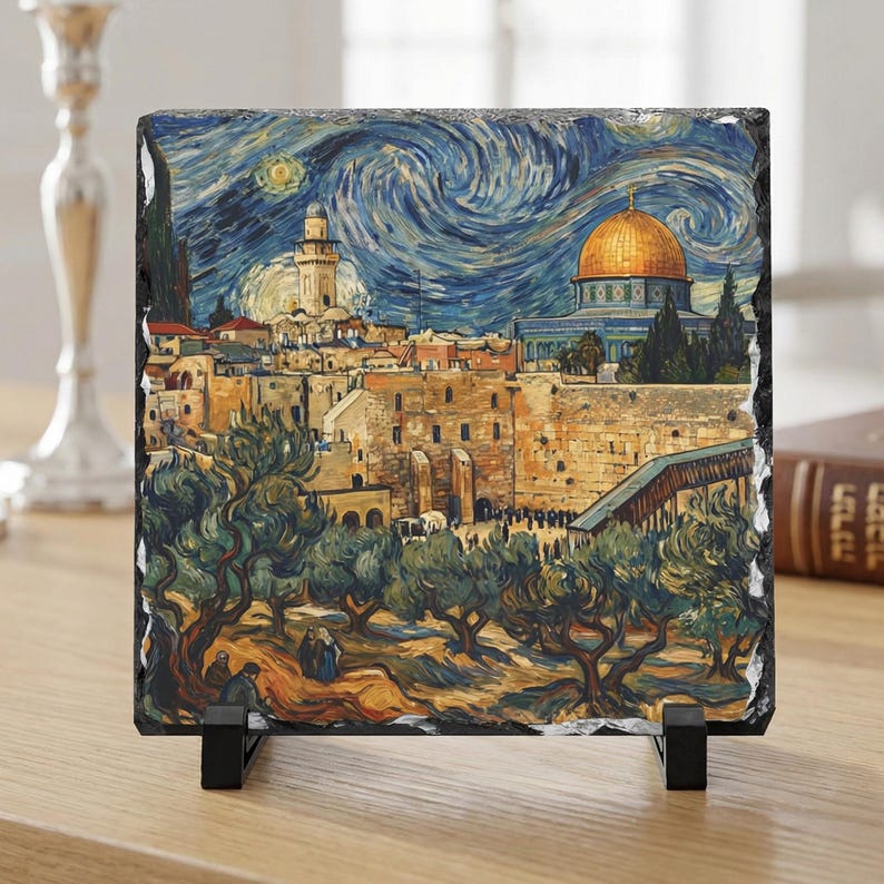 May include: A square, framed art piece depicting a cityscape under a swirling, starry night sky. The artwork features a golden-domed building, stone structures, and olive trees in the foreground. The piece is mounted on a black stand.