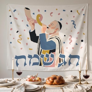 Puede incluir: Un tapiz de pared blanco con una ilustración estilizada de una persona soplando un shofar, rodeada de formas de confeti de colores. Debajo de la figura, el texto hebreo "חג שמח" está impreso en letras azules grandes. El diseño utiliza una paleta de azul, rosa, amarillo y negro.