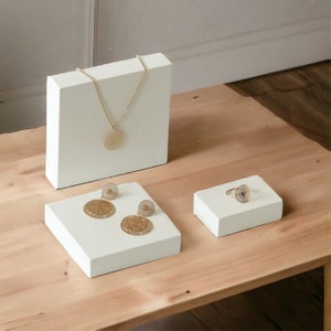 Può includere: Un set di gioielli color oro composto da una delicata collana a catena con un ciondolo circolare in filigrana, un paio di orecchini pendenti circolari abbinati con intricati motivi traforati e un anello con un design in filigrana coordinato.