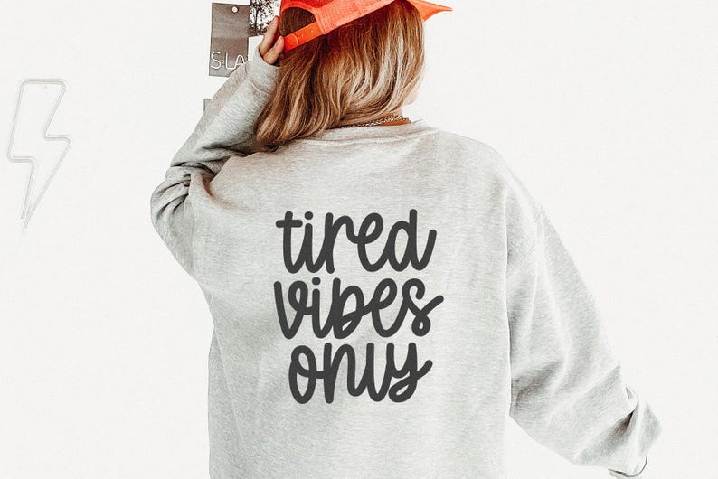 Op de afbeelding: Een grijs sweatshirt met de tekst "tired vibes only" gedrukt op de achterkant in zwart.