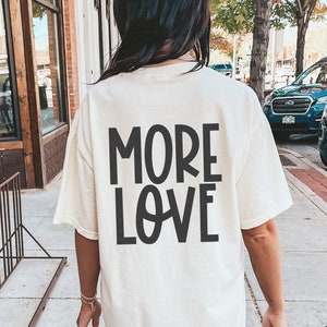 May include: A white t-shirt with the text "MORE LOVE" printed in black on the back.