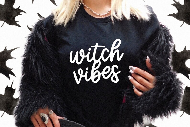 Puede incluir: Camiseta negra con las palabras "witch vibes" en escritura blanca. La persona lleva una chaqueta de piel sint&eacute;tica negra. El fondo tiene un patr&oacute;n de formas de hojas negras.