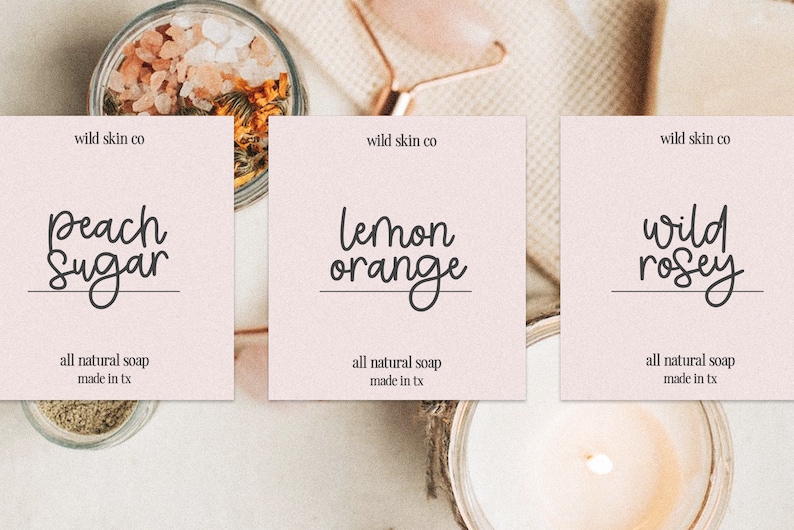 Peut inclure: Trois &eacute;tiquettes roses avec du texte noir sur fond blanc. Les &eacute;tiquettes indiquent "wild skin co" et pr&eacute;sentent diff&eacute;rents parfums : "Peach Sugar", "Lemon Orange" et "Wild Rosey". Chaque &eacute;tiquette comprend &eacute;galement le texte "all natural soap made in tx".