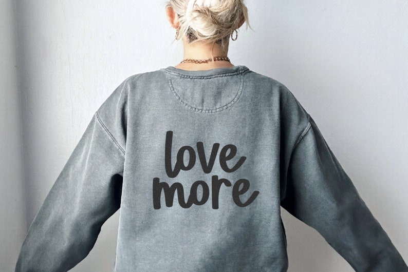 May include: A gray sweatshirt with the text "love more" printed on the back in black.