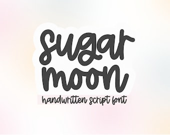 May include: A sticker with the words "Sugar Moon" in a dark gray, handwritten script font. Below the words is the text "handwritten script font" in a smaller, lighter font. The background is a soft gradient of pink, yellow, and white.