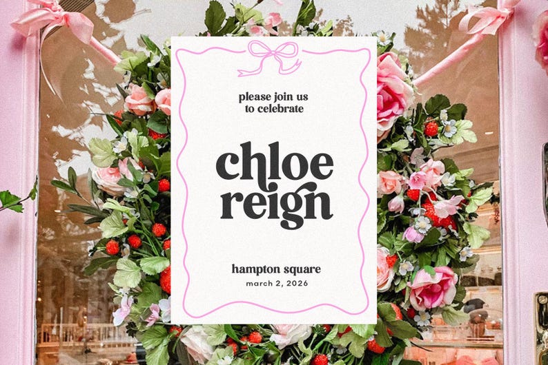 May include: A floral wreath surrounds a white invitation with pink trim. The invitation reads "please join us to celebrate Chloe Reign" and includes the location and date. Pink bows and door frame are visible.