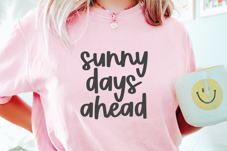 May include: A pink t-shirt with the text "sunny days ahead" in black lettering.