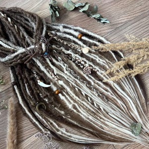 May include: Brown and white synthetic dreadlocks with various charms and beads. The dreadlocks are arranged in a loose braid with the ends flowing freely.