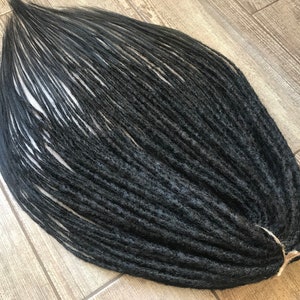 May include: A bundle of black synthetic dreadlocks, ready to be added to natural hair for a unique hairstyle.